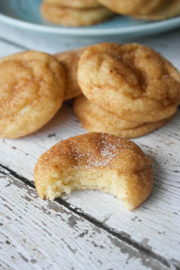 some sugared doughnuts are on a white wooden table next to a blue plate