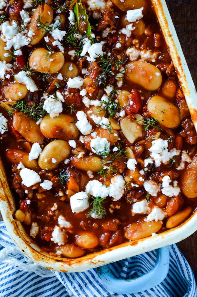 a casserole dish filled with beans and feta cheese on a blue towel