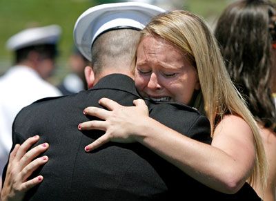 a woman is hugging a man in uniform