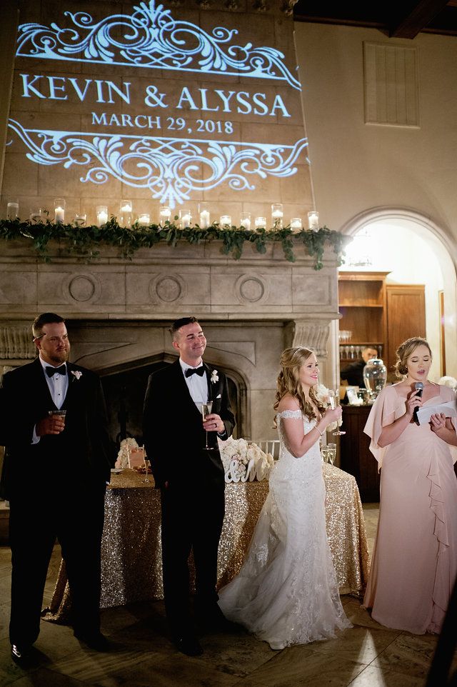 a group of people standing around each other in front of a fire place with candles on it