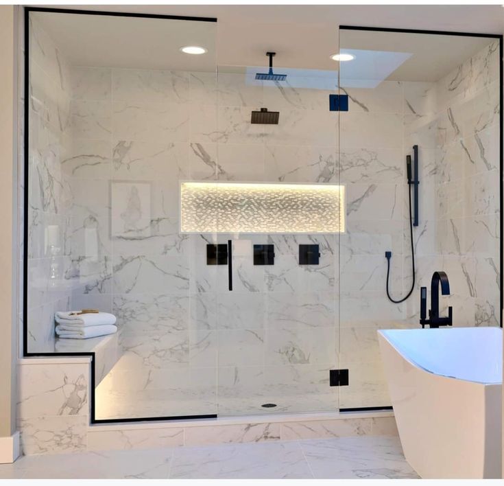 a white bathroom with marble walls and flooring, along with a walk in shower