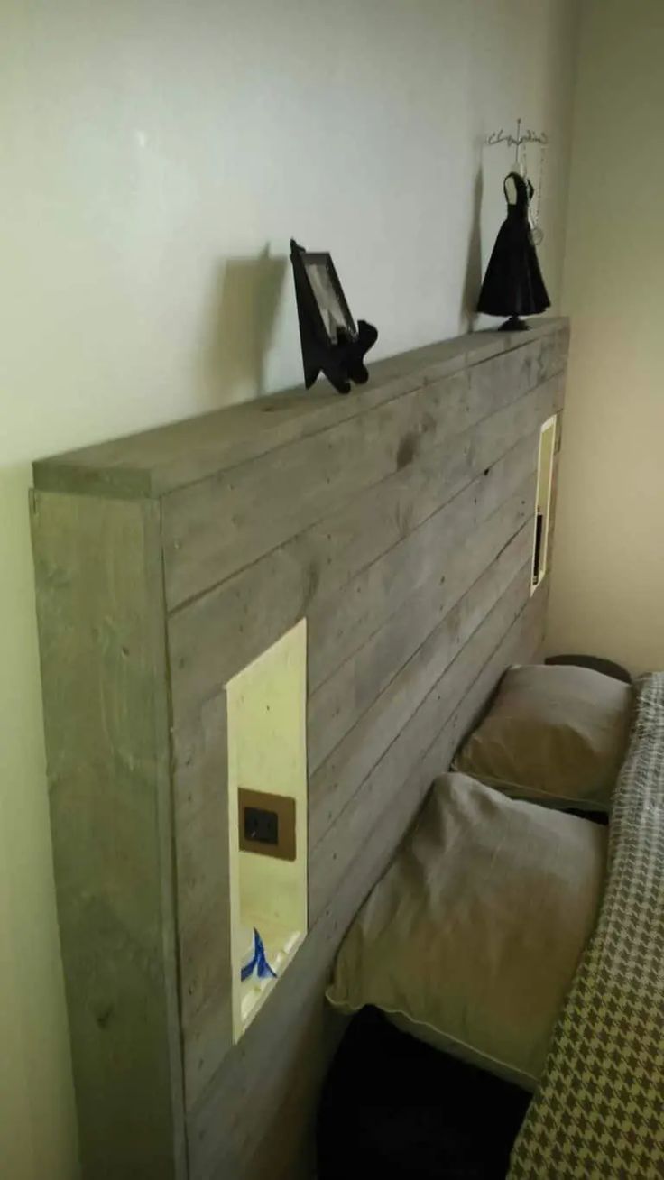 there is a bed made out of wood with two black cats on the headboard