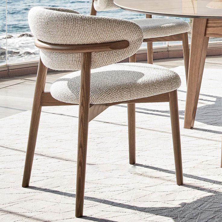 a table with two chairs and a vase on top of it next to the ocean