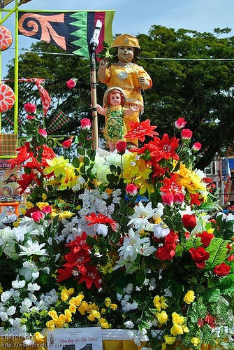 there are many colorful flowers and statues in this parade float, including one with a child on it