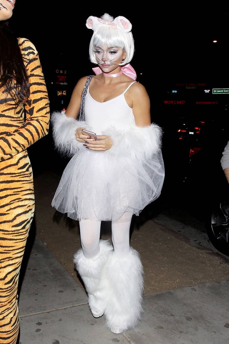 two women dressed in costumes walking down the street at night, one wearing a tiger costume