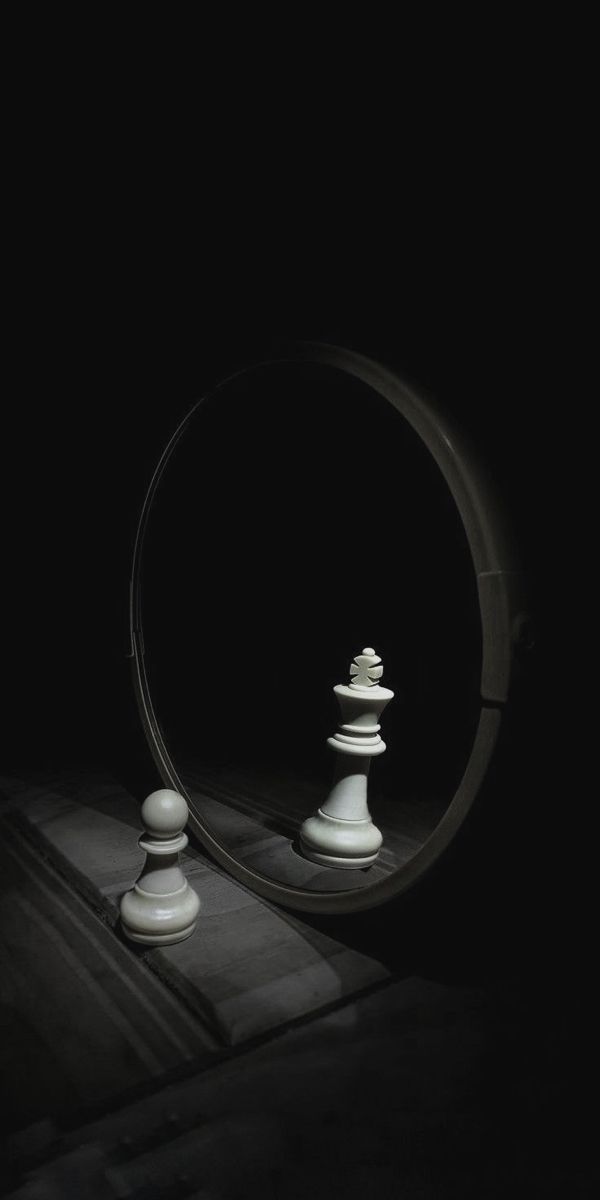 a mirror with some white chess pieces in the middle and light coming from behind it