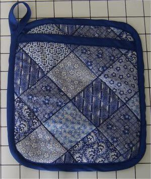 a blue and white patchwork purse sitting on top of a tile floor next to a ruler