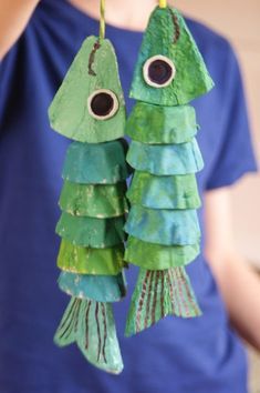 a person holding two paper fish with googly eyes