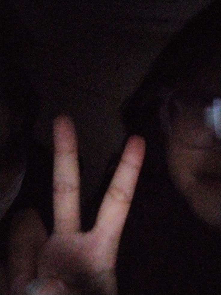 two people making the peace sign with their hands in front of them at night time