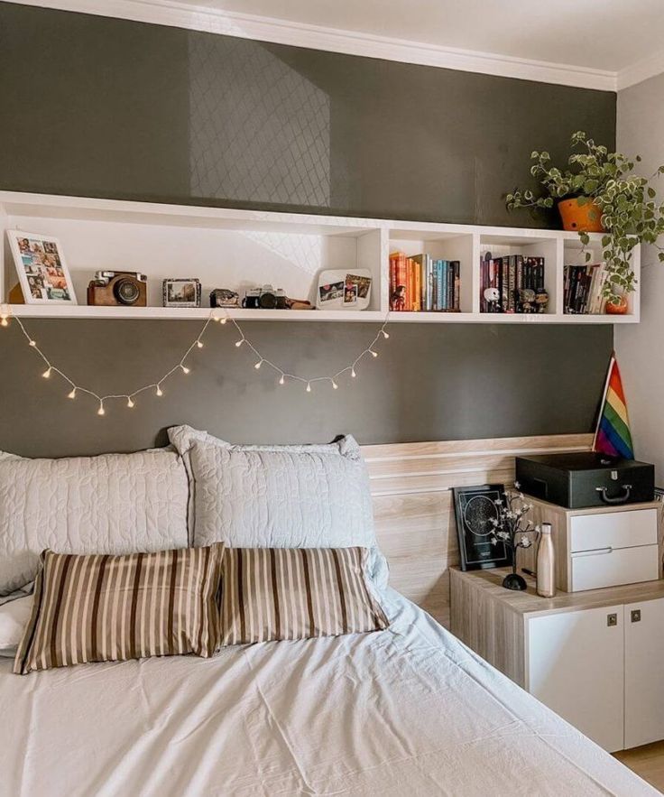 there is a bed with white sheets and pillows on the headboard, along with bookshelves