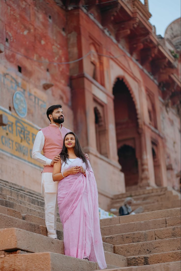 a man and woman standing on steps in front of an old building