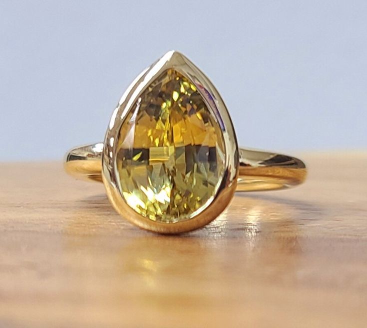 This stunning vintage ring is crafted from 14k yellow gold and features a 3.54CT natural yellow sapphire in pear cut and, a gorgeous bezel setting. The ring is perfect for engagement or anniversary occasions and has a cocktail style with a nature theme. The yellow sapphire is loupe clean. Gorgeous vintage 14k yellow gold engagement ring natural yellow sapphire in a pear shape. Center set natural yellow sapphire weight 3.54ct. size 11.3x8mm gorgeous yellow color,nice luster very lively, brilliant Gold Sapphire Ring Umbrella, Pear-shaped Yellow Gold Sapphire Ring, Yellow Pear Shaped Fine Jewelry Rings, Fine Jewelry Yellow Gold Sapphire Ring Pear-shaped, Fine Jewelry Yellow Gold Pear-shaped Sapphire Ring, Fine Jewelry Yellow Pear-shaped Ring, Heirloom Yellow Gold Pear-shaped Ring, Heirloom Yellow Gold Pear Shaped Ring, Yellow Teardrop Wedding Ring