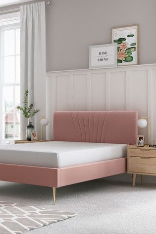 a pink bed frame in a bedroom with white walls and carpeted flooring on the side