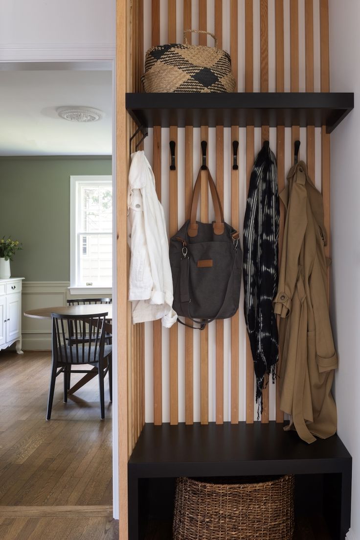 a coat rack with two coats hanging on it and a handbag sitting on the top shelf