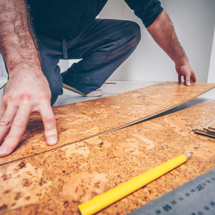 a man is working on a piece of plywood with a yellow handled knife in his hand