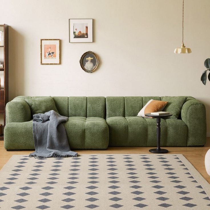 a green couch sitting on top of a wooden floor next to a white rug and table