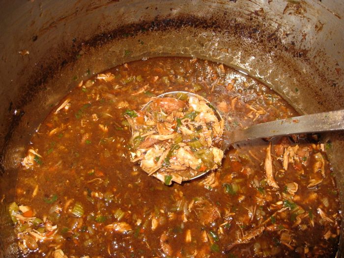 a pot filled with stew and a ladle in the bottom left hand corner is a spoon