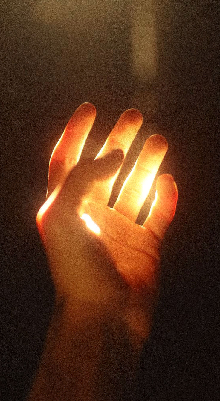 a person holding their hand up in the air with light coming from it's fingers