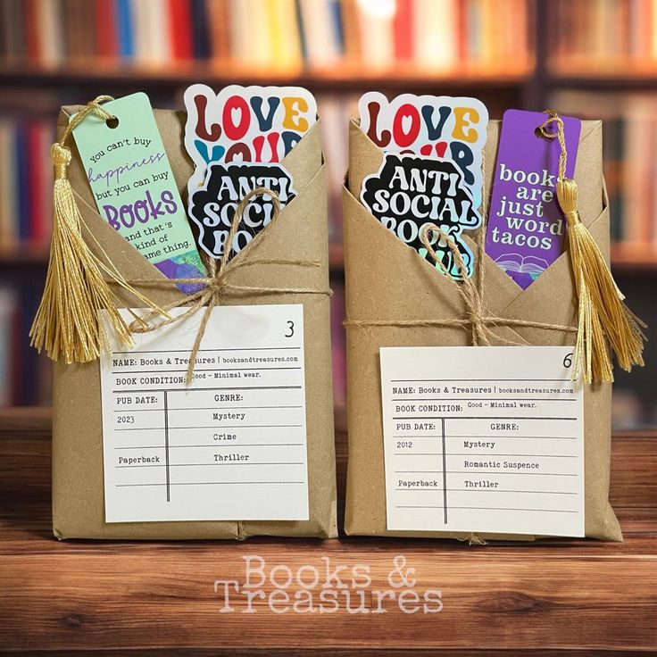 two brown paper bags with tags and tassels on them sitting on a table in front of bookshelves