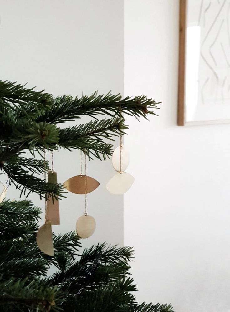 a christmas tree with ornaments hanging from it's branches in front of a white wall