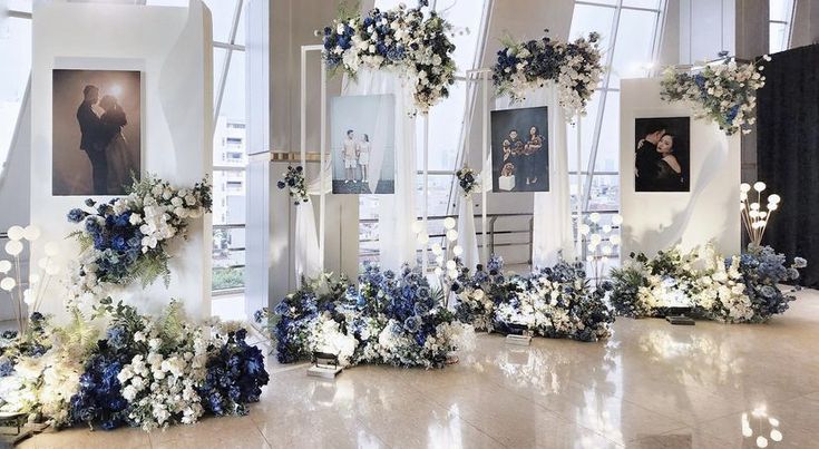 an arrangement of blue and white flowers on display in front of large windows at a wedding