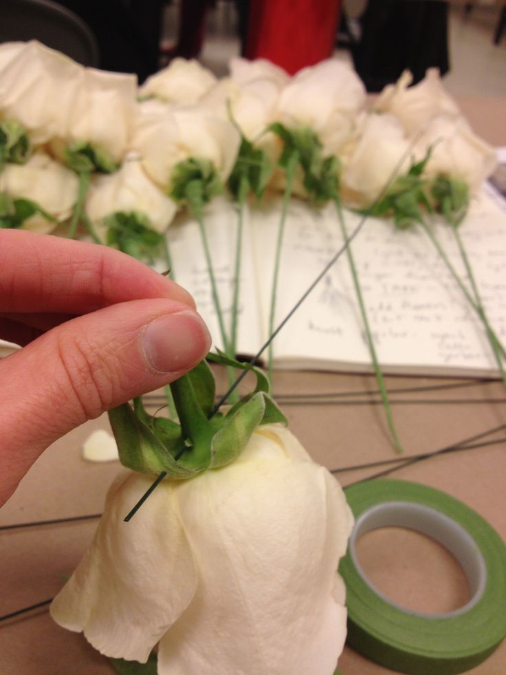 a person is holding up some flowers on a table with tape and scissors in front of them