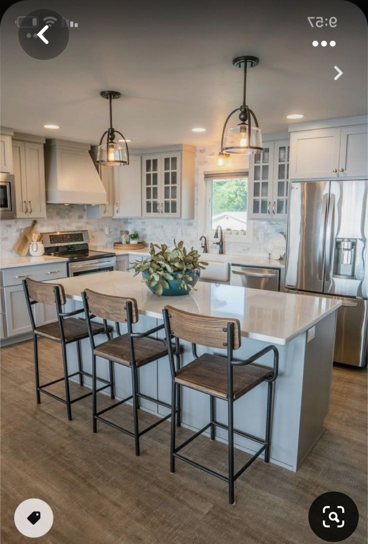 an image of a kitchen setting with stools and island in the middle, surrounded by stainless steel appliances