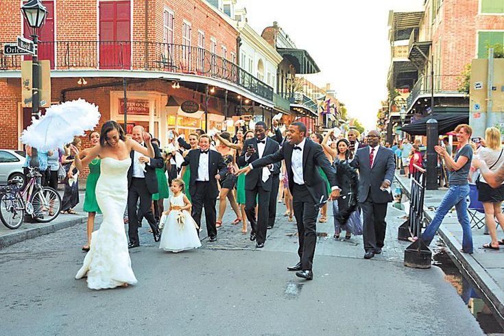 a bride and groom walk down the street in front of their wedding party as photographers take pictures