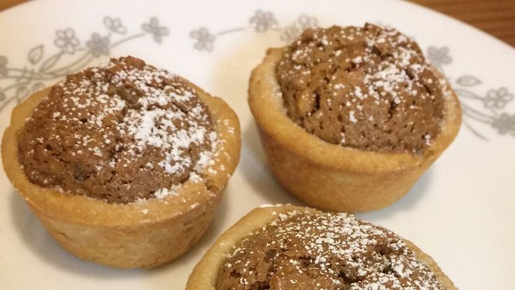 three cupcakes on a plate with powdered sugar