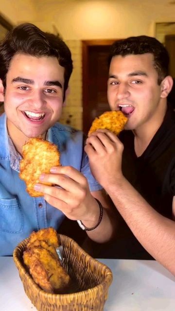 two men sitting at a table eating food