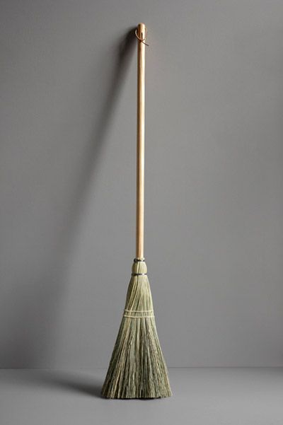 a broom leaning up against a gray wall