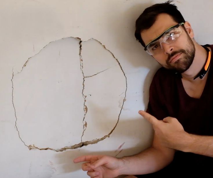 a man pointing at a hole in the wall