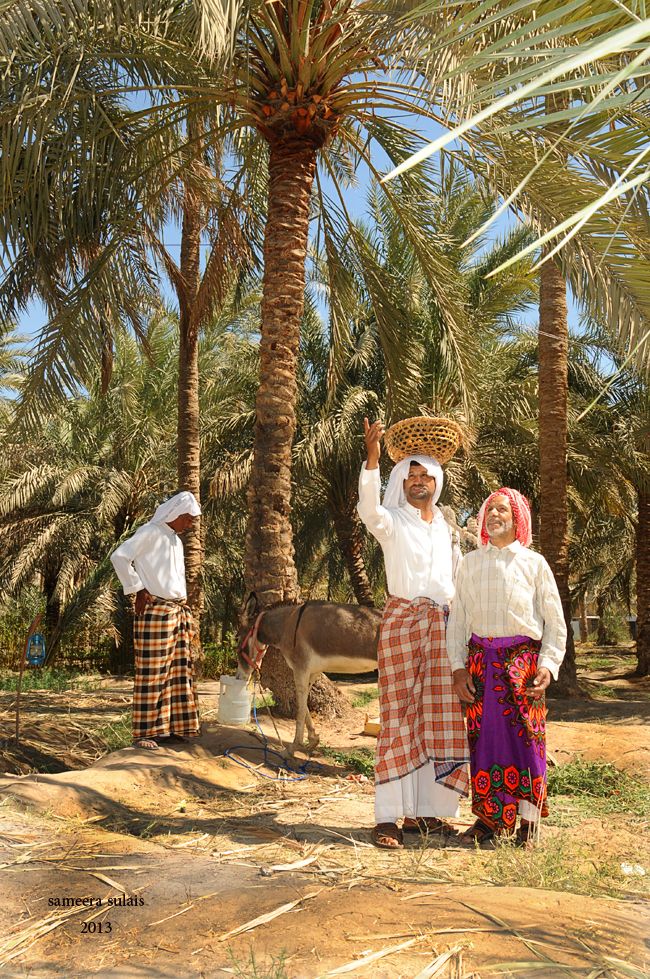 two women are standing under palm trees with baskets on their heads