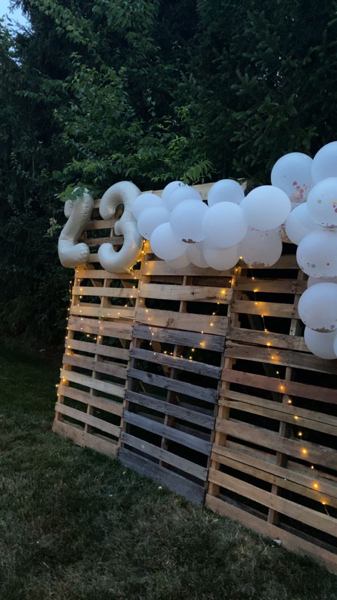 some balloons are hanging on the side of a wooden pallet with lights around them