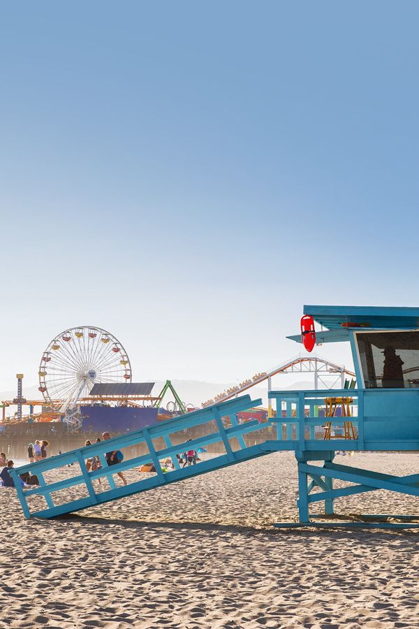 a lifeguard tower on the beach with people in it and a ferris wheel in the background