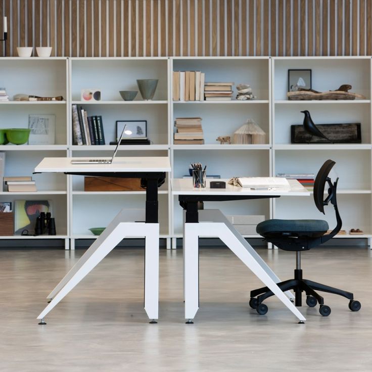 two white desks with black chairs in front of shelves filled with books and office supplies