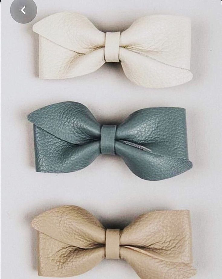 three different types of leather bow ties on a white surface, one is green and the other is beige