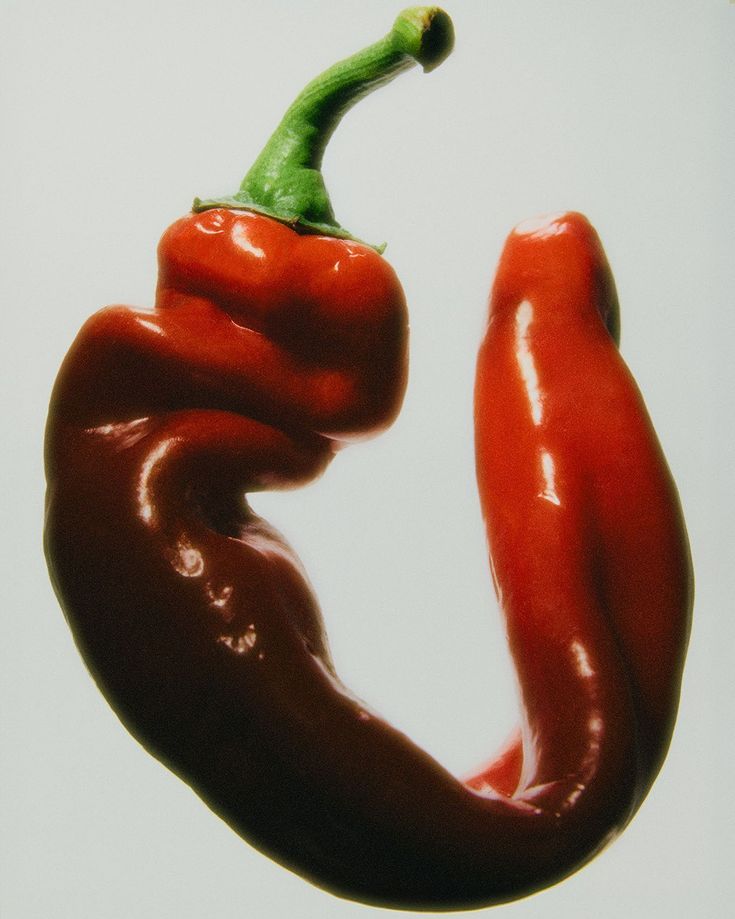 a close up of a red hot pepper on a white background with the top half turned upside down