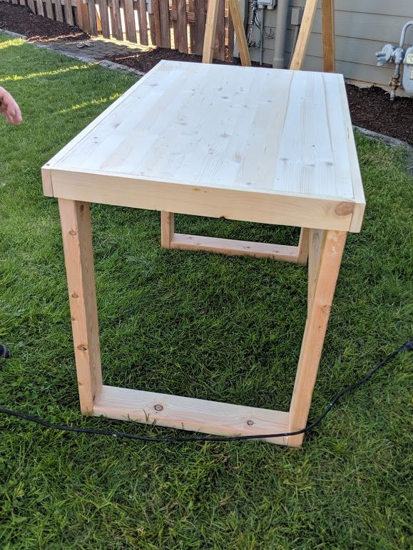 a wooden table sitting on top of a lush green field