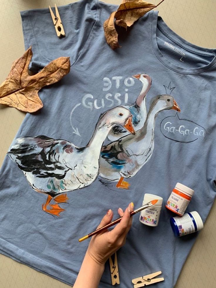 someone is painting two ducks on a t - shirt with acrylic paintbrushes