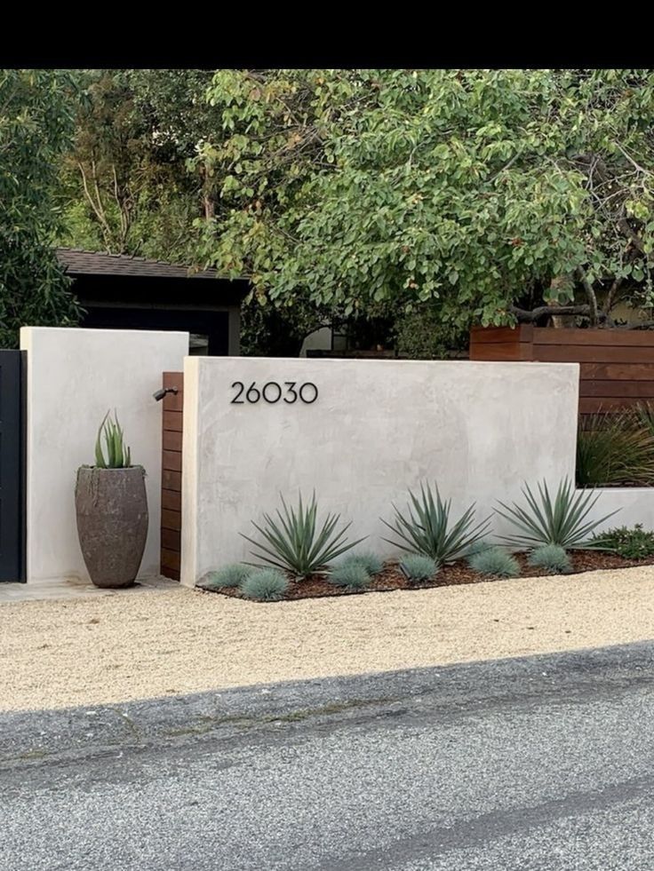 an entrance to a house with plants and trees in the front yard, next to it is a sign that reads 2000