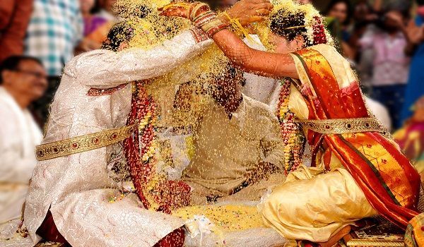 two people dressed in white and yellow sitting on the ground with their arms around each other