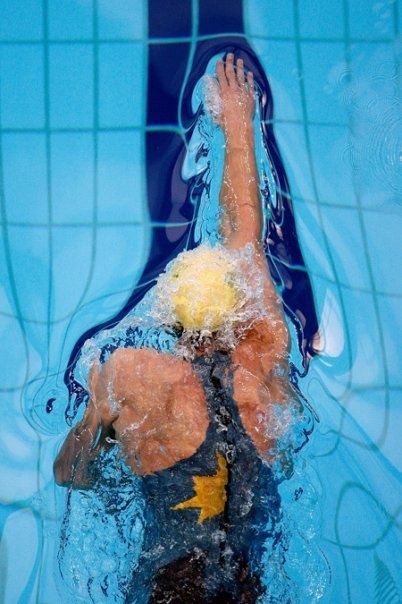 a man swimming in a pool with his hand up to the water's edge