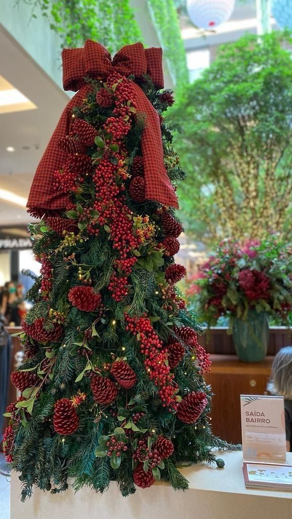 a christmas tree made out of pine cones and red berries with a bow on top