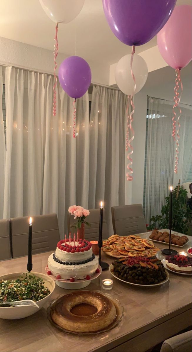 a table topped with lots of food and balloons