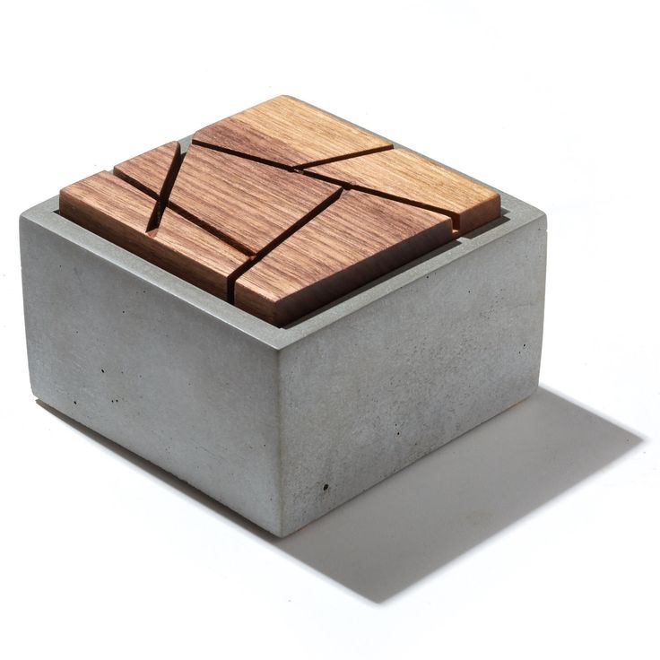 a wooden object sitting on top of a cement block with a square design in the middle