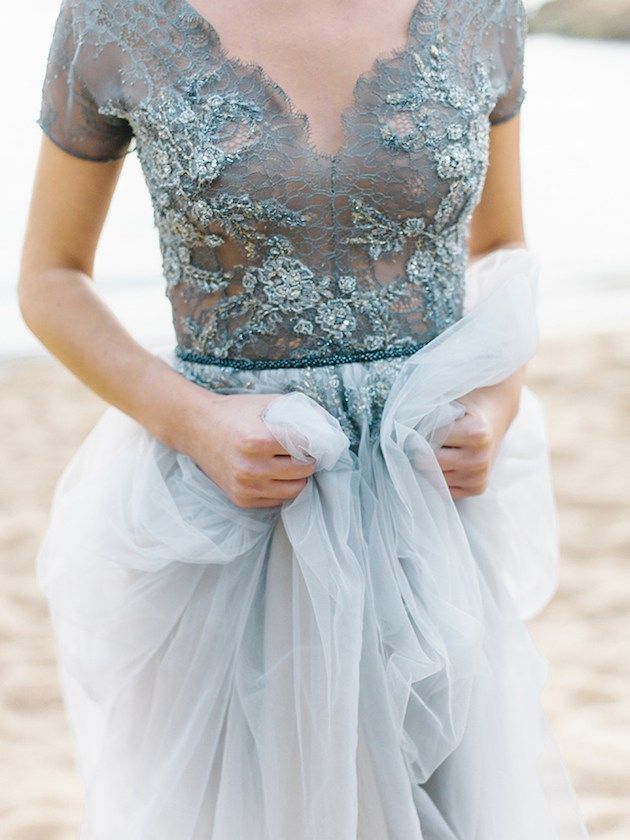 a woman is walking down the street wearing a dress with sheer sleeves and a bow around her waist