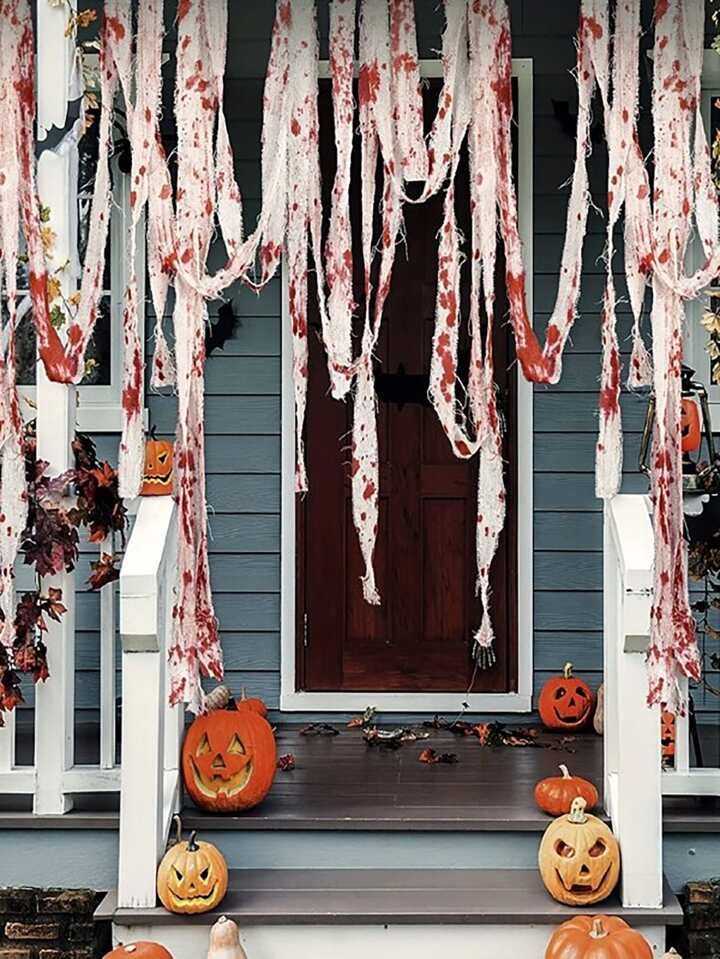 a porch decorated for halloween with pumpkins and icicles hanging from the front door