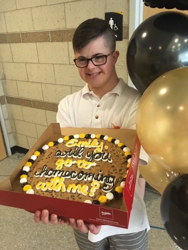 a young boy holding a birthday cake in front of balloons