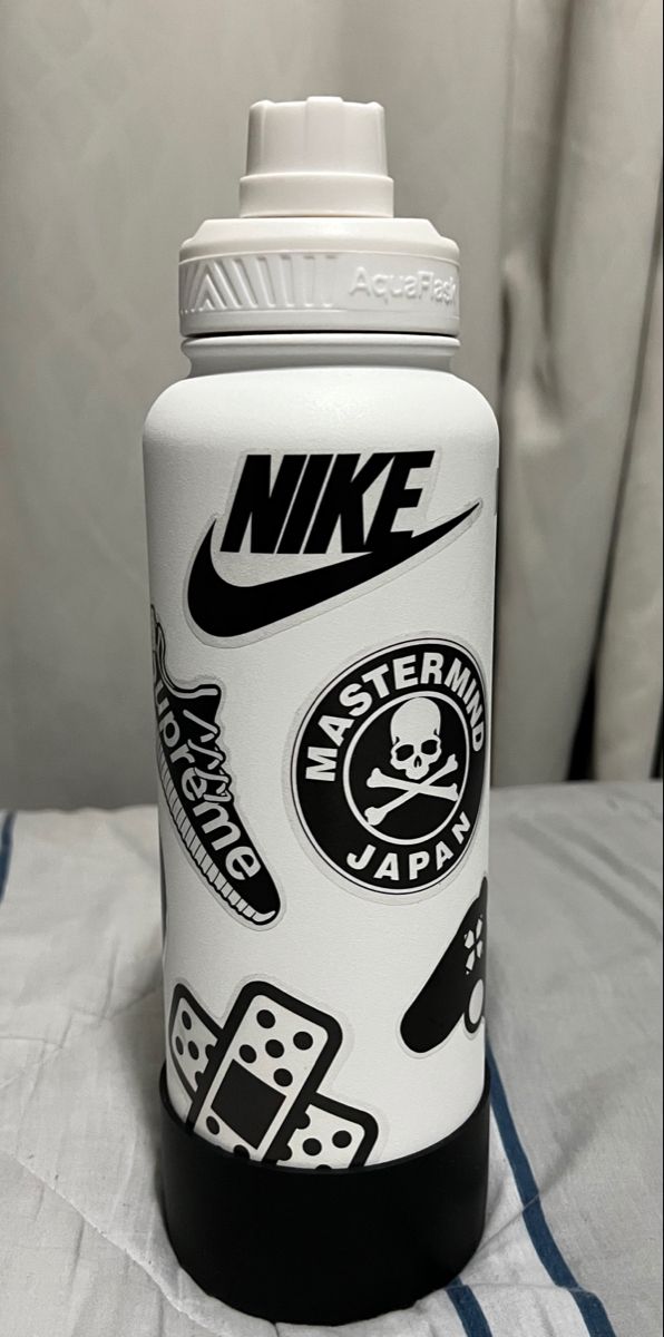 a white and black nike water bottle sitting on top of a bed